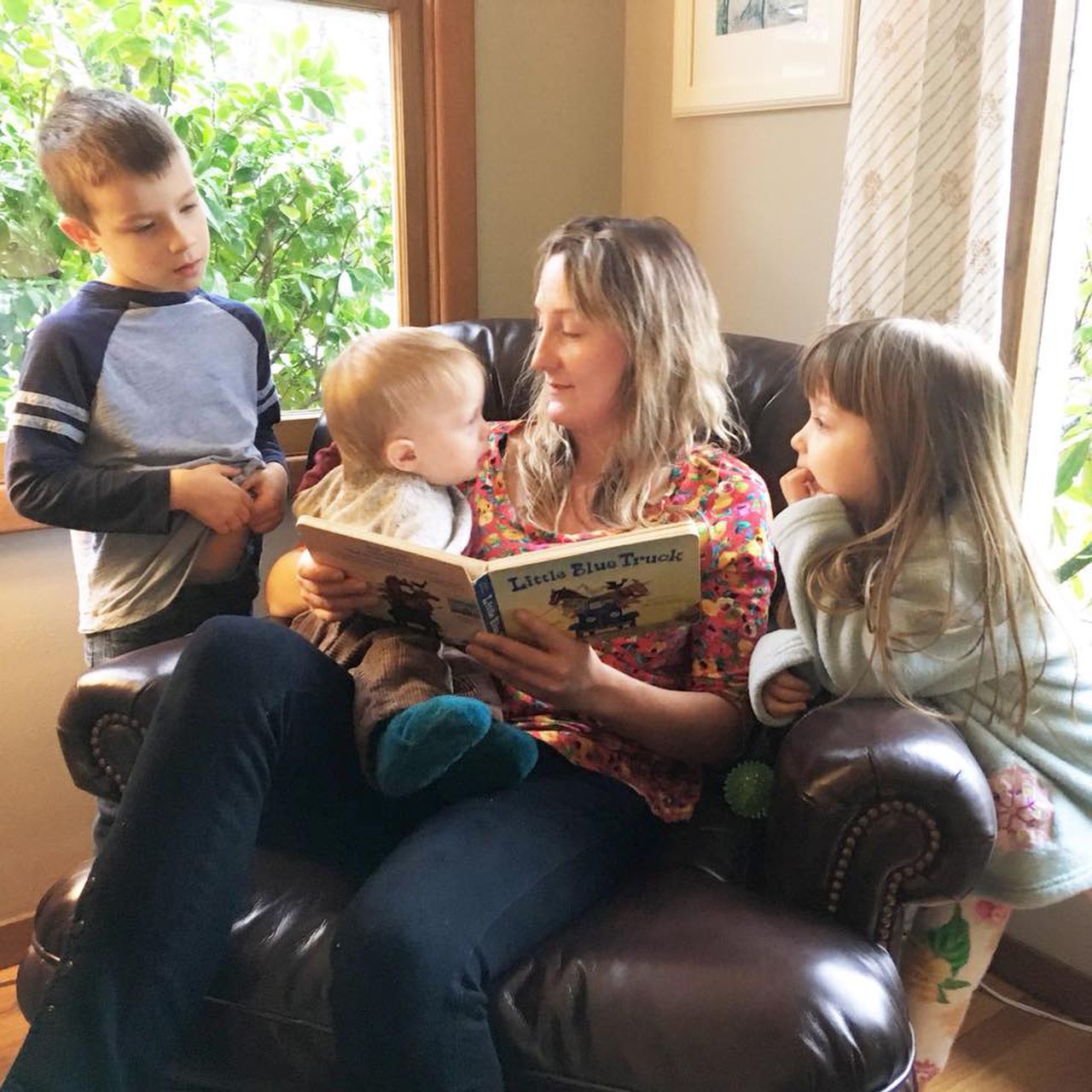 a woman reads to three kids