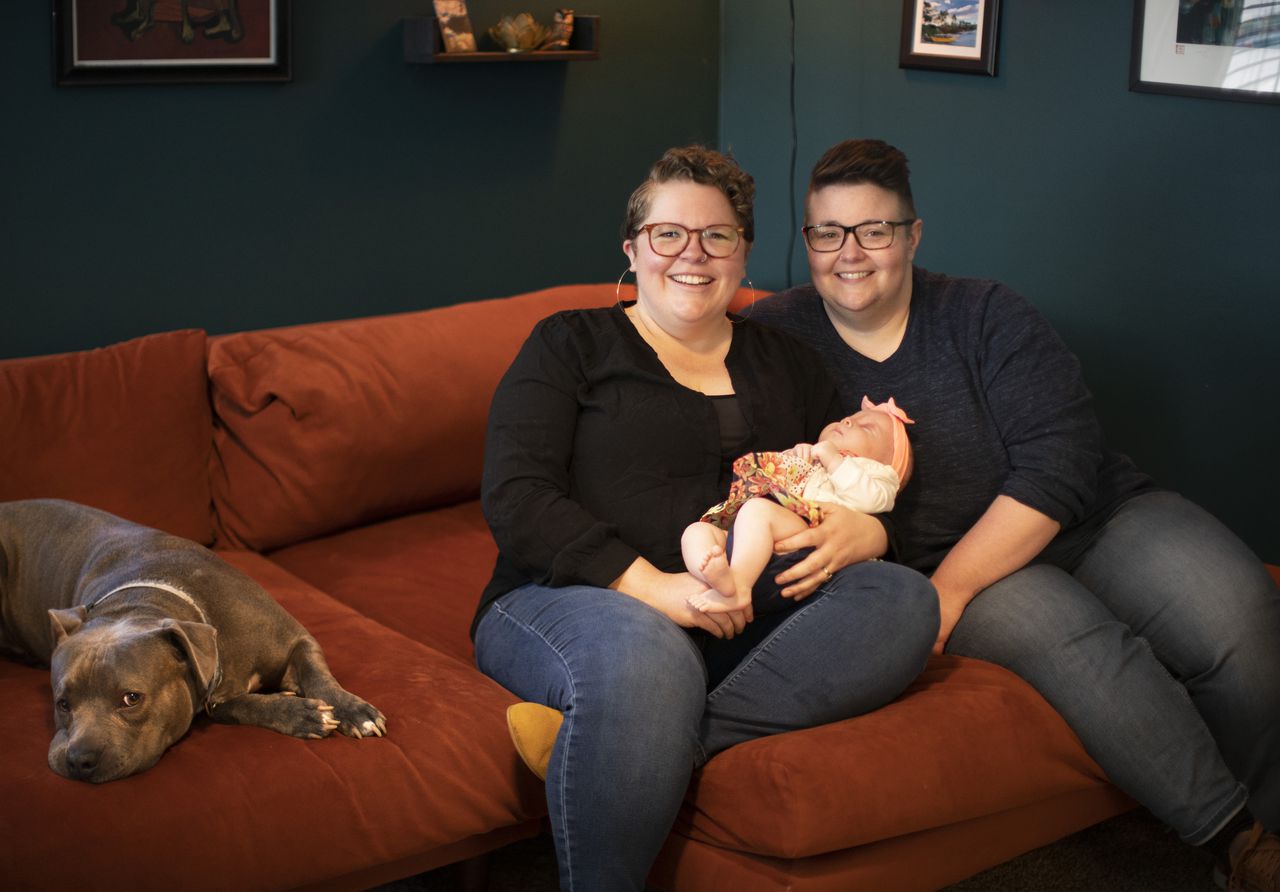 two women on a couch with a baby and a dog