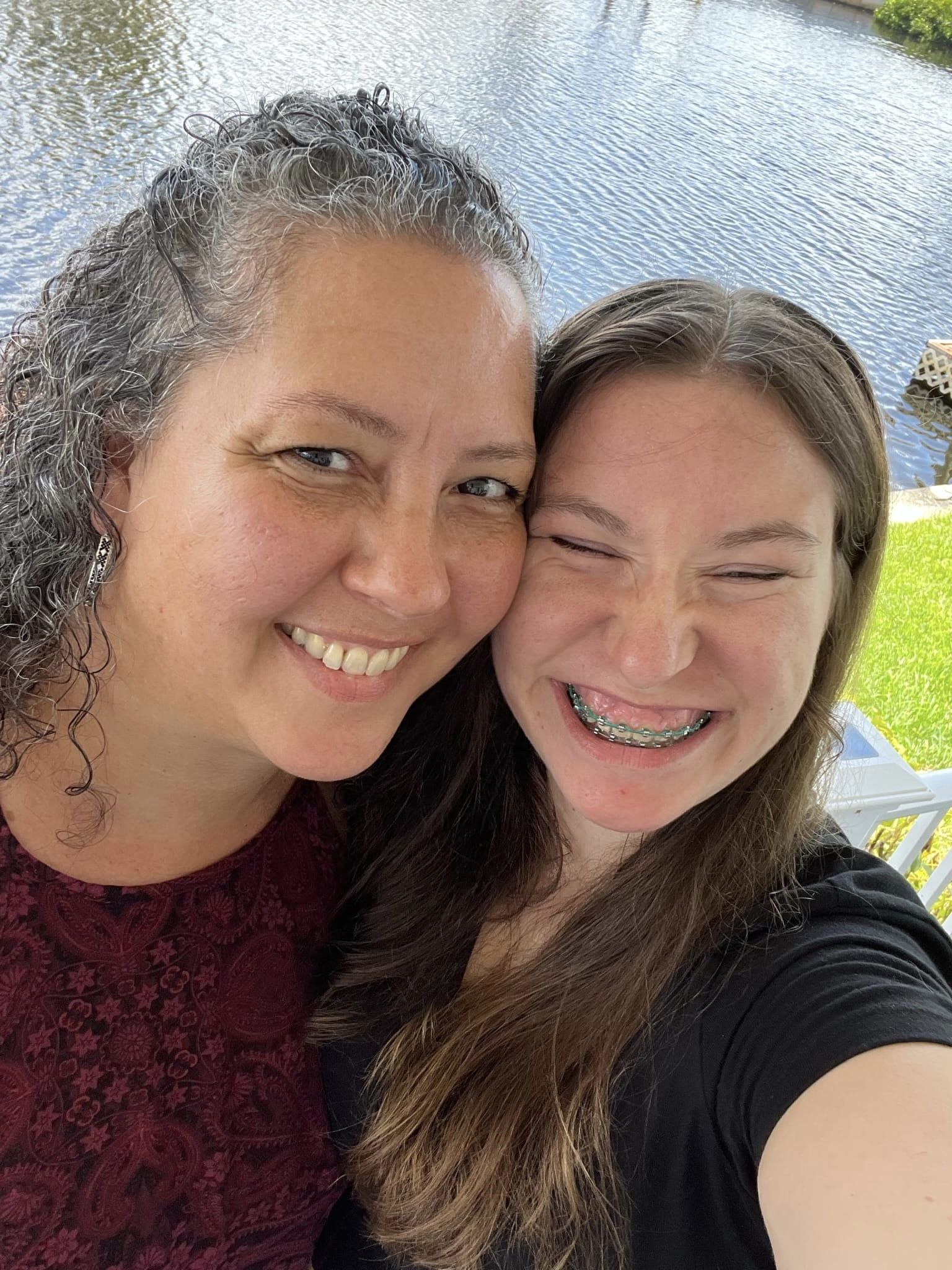 Giselle Espinet (left) and her adopted daughter, Liliana, hug each other tightly, cheek to cheek. Liliana’s arm is raised to take the selfie-style portrait of the two.