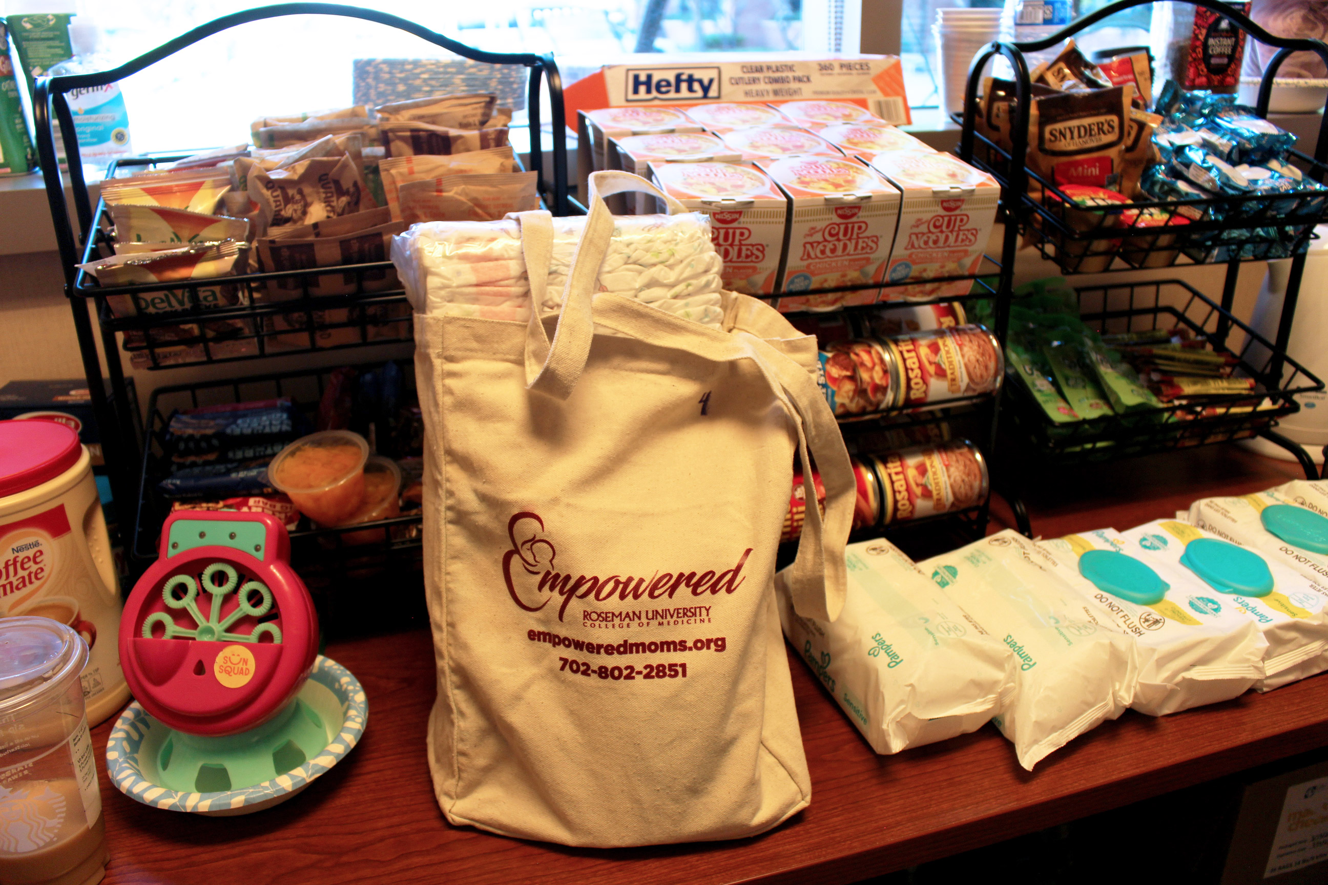 A photo of a tote bag surrounded by baby wipes and rows of snacks.