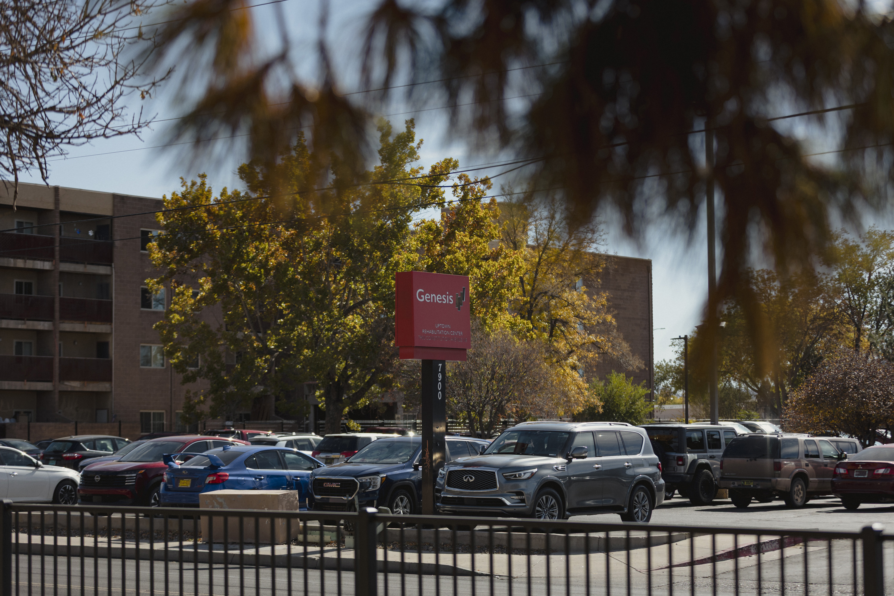 A red sign with the word "Genesis" stands in a parking lot